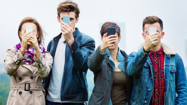 Jovens com o celular na frente do rosto