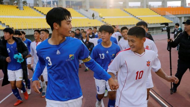 Players of the April 25 Sports Club of North Korea (white) and the Gangwon-do team of South Korea (blue) run together