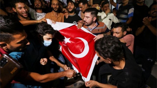 متظاهرون يحرقون العلم التركي أمام مركز للتأشيرات التركية في كربلاء عقب القصف الصاروخي