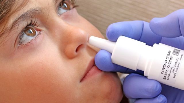 Un médico aplica una vacuna nasal a una niña