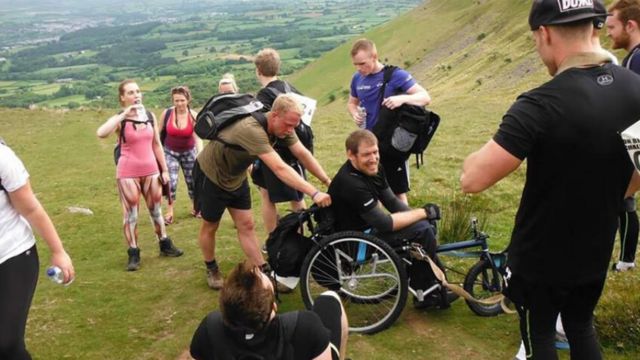 Jamie in a wheelchair with a group on a mountain