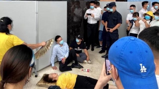 2021年9月，恒大总部门前，一位高管瘫坐门前，面对抗议者此起彼伏的“还钱”呼声——成为这个中国最大房企陷入危机的经典一幕。(photo:BBC)