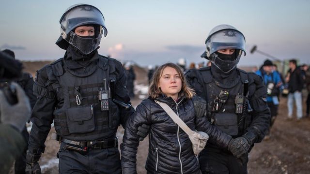 Greta Thunberg cercada por dois policiais