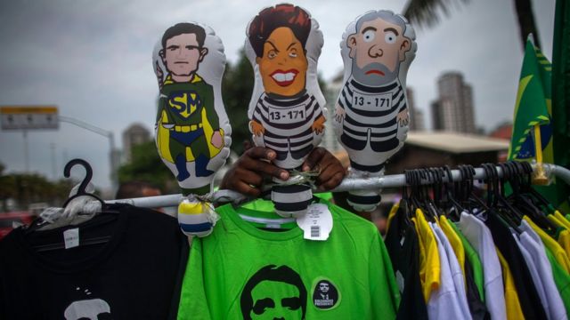 Camisetas de Bolsonaro e bonecos infláveis de um 'super-heroi' Sergio Moro, e de Dilma e Lula presidiários, em frente ao condomínio onde vive o futuro presidente, no Rio