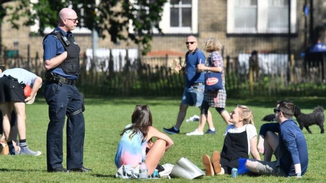 Police speak to people gathering in a park in England