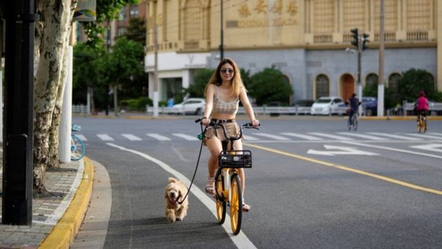مواطنة في شنغهاي تركب دراجة هوائية وإلى جانبها كلبها