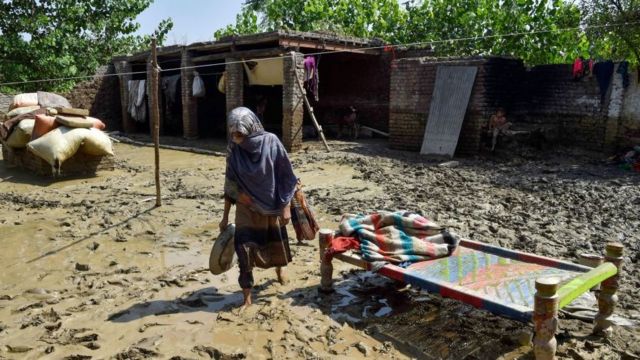 امرأة متضررة من الفيضانات تمشي خارج منزلها المدمر في قرية جيندي في منطقة تشارسادا في خيبر بختونخوا في 1 سبتمبر 2022.