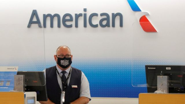 Funcionário da American Airlines de máscara atrás de balcão da companhia