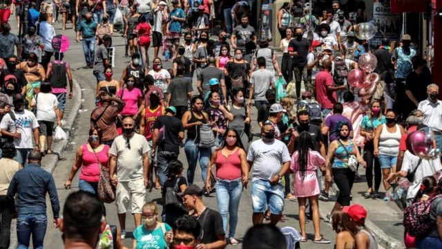 Dozens of people walk along a shopping street in downtown São Paulo, Brazil, 7 October 2020.