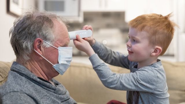 Niño tomándole la fiebre a su abuelo