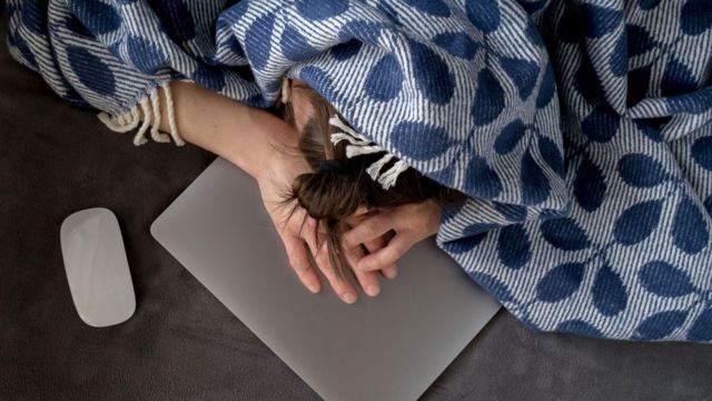 Mulher deitada com a cabeça em cima do laptop