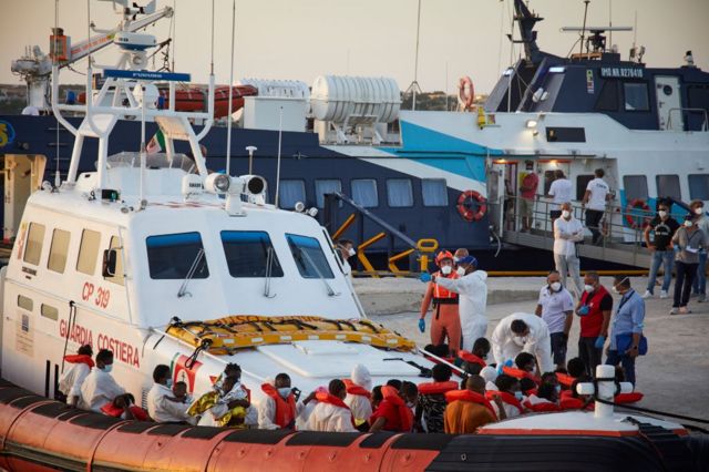 İtalya'da Lampedusa sahili yakınında, Louis Michel gemisi tarafından Libya'dan kurtarılmış bir grup göçmenin karaya çıkarılmasına yardım ediyor