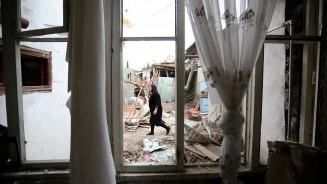 Woman walks past house damaged by shelling in the Azerbaijani city of Ganja - 6 October