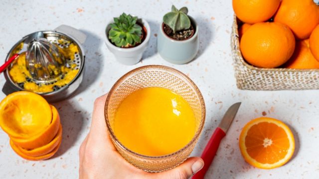 Vaso de jugo de naranja y naranjas
