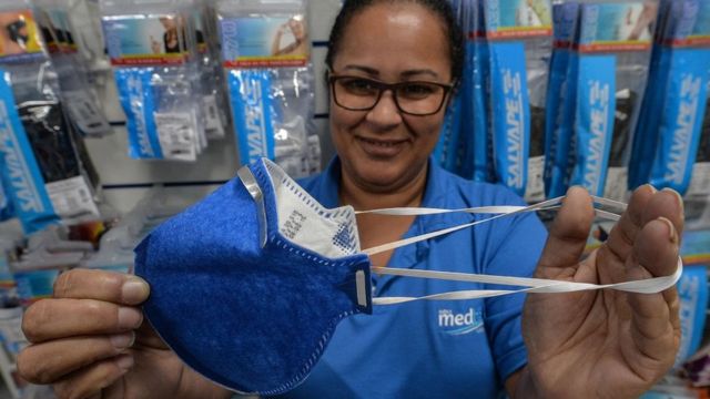 A worker at a medical supply store in Brazil demonstrates the popular model of face mask shoppers are buying