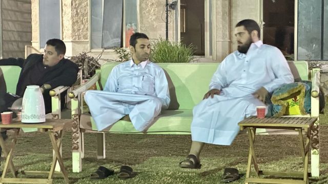 Dos qataríes con un thaub blanco conversan mientras ven el fútbol.