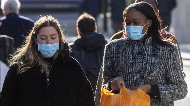 Two women wearing face masks walk along a street in London, on 21 October 2021