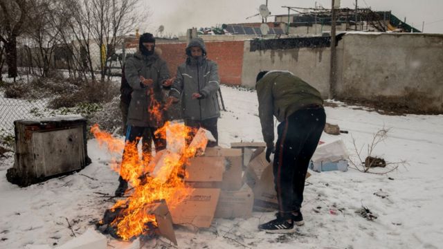 People stand around a bonfire in Cañada Real, outside of Madrid