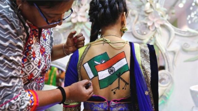 भारत और पाकिस्तान के झंडे बनवाती एक युवती