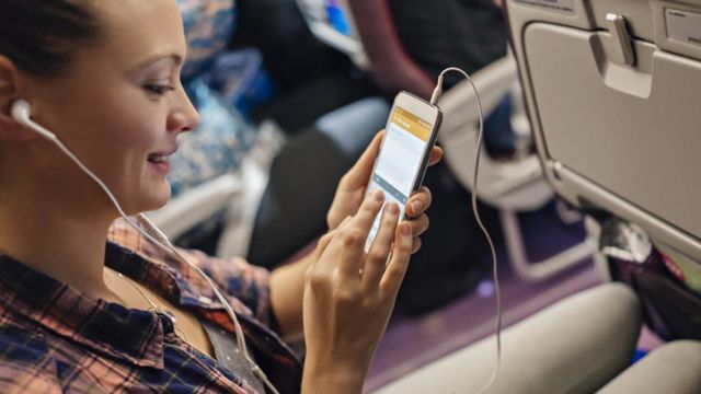 Una mujer maneja su celular dentro de un avión