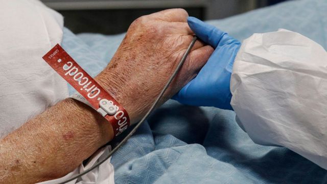 Profissional de saúde segura a mão de paciente com covid-19 no hospital