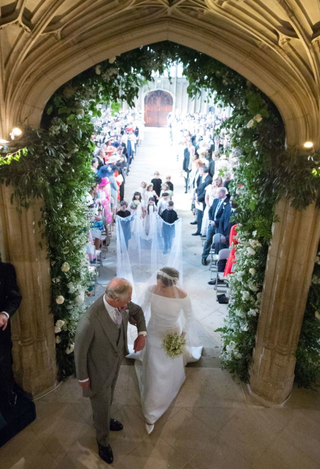 Meghan Markle, accompanied by Britain's King Charles III, walks down the aisle in St George's Chapel, Windsor Castle, during her wedding ceremony to Prince Harry on 19 May 2018.