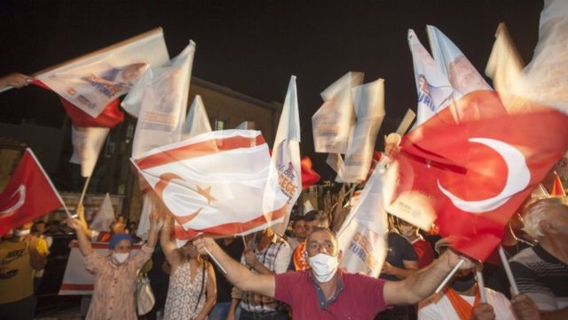 A person waving flags of Turkey and TRNC