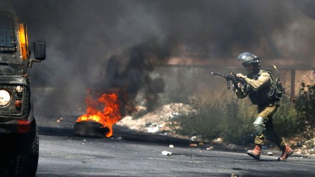 An Israeli soldier gets into position during clashes with Palestinian demonstrators in the West Bank