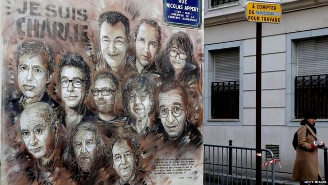 पैरिस में एक जगह दीवार पर बनाई गई शार्ली एब्डो के मारे गए कर्मचारियों को समर्पित एक कलाकृति