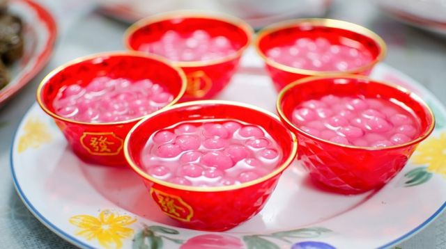 Small red bowls decorated with Chinese inscriptions, and full of brightly coloured tangyuan (sweet dumplings made of glutinous rice and served in syrup)