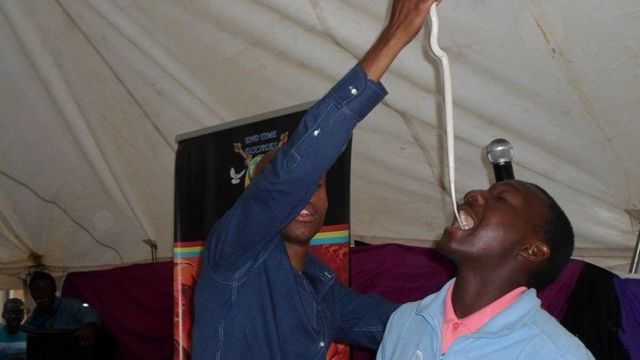 Puel Mnguni akiingiza nyoka katika kinywa cha muumini