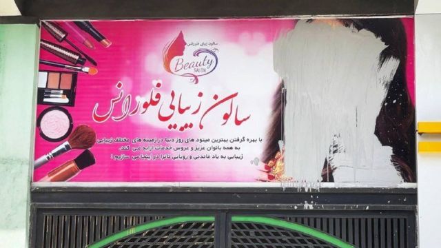 A billboard poster on which the face of a woman has been scratched out