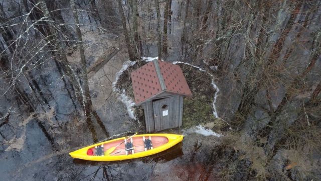 Una casita y una canoa en medio de un bosque vistas desde el aire