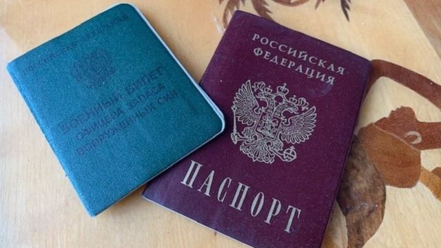 Fotografia colorida mostra um passaporte azul e um roxo