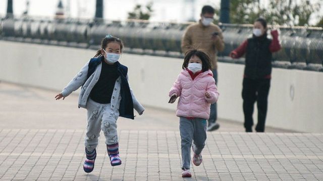 two little girls running wearing masks