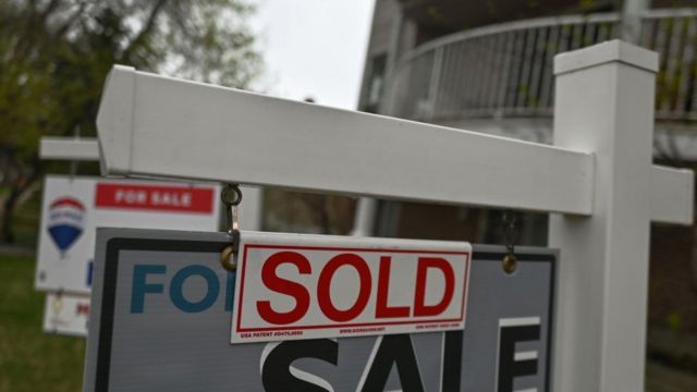 Foto de una pegatina que dice "vendido" en un cartel de "se vende" en el exterior de una casa en Canadá.
