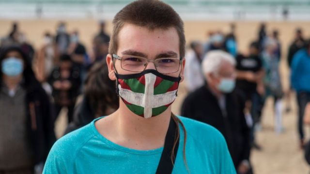 Manifestante con tapabocas con la bandera vasca