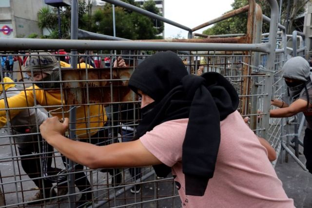 Manifestantes mueven una valla protectora en en medio de las protestas contra el gobierno de Guillermo Lasso en Quito, Ecuador.