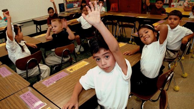Varios niños levantan la mano en un aula escolar