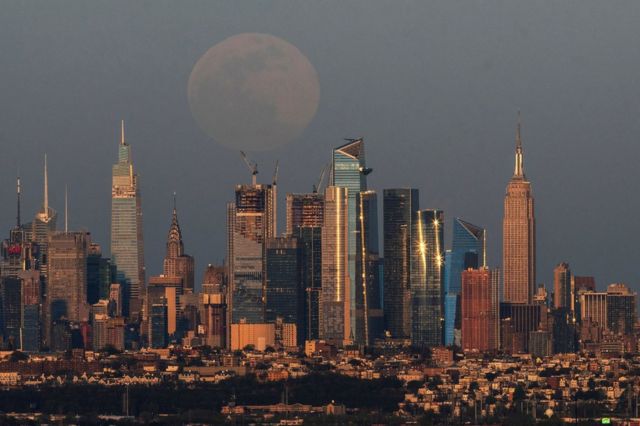 The skyline of New York and the Empire State Building with the pink supermoon in the sky