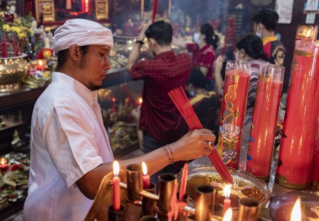 在印度尼西亚巴厘岛库塔，一名男子在一座寺庙举行的农历新年庆祝活动中点燃香火。