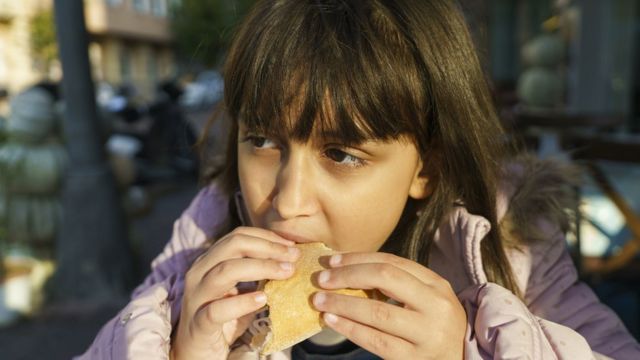 Little girl eating hamburger.