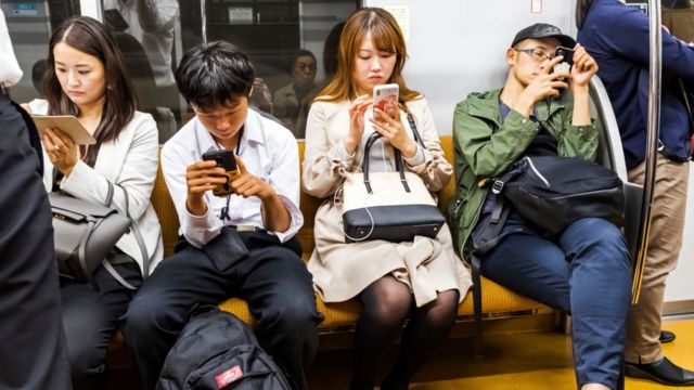 Passageiros sentados em metrô de Tóquio