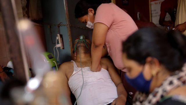 امرأة هندية تضغط على صدر والدها الذي يعاني صعوبة في التنفس