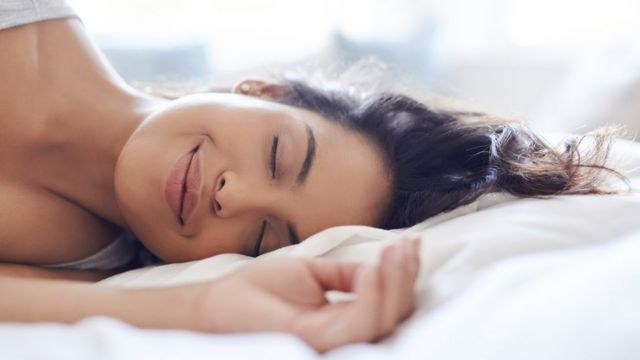 Une femme qui dort sur un lit en souriant