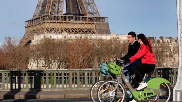 زوجان يركبان دراجتهما بالقرب من برج إيفل قبل حظر التجول، باريس