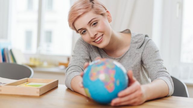 Una mujer sostiene un globo terráqueo.