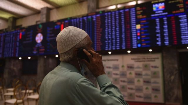 A stockbroker talks on his mobile phone as he monitors the latest share prices at the Pakistan Stock Exchange (PSX) in Karachi on March 7, 2022