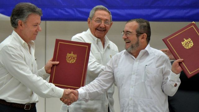 Президент Колумбии Хуан Мануэль Сантос и лидер повстанческой группировки ФАРК, известный под псевдонимом Тимоченко, пожимают руки в присутствии президента Кубы Рауля Кастро