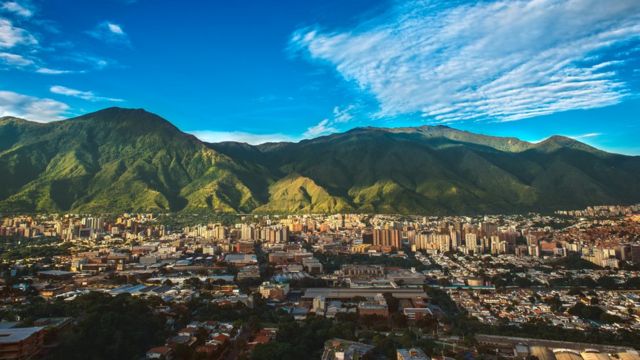 Ampla paisagem de Caracas, com montanhas ao fundo e dia ensolarado